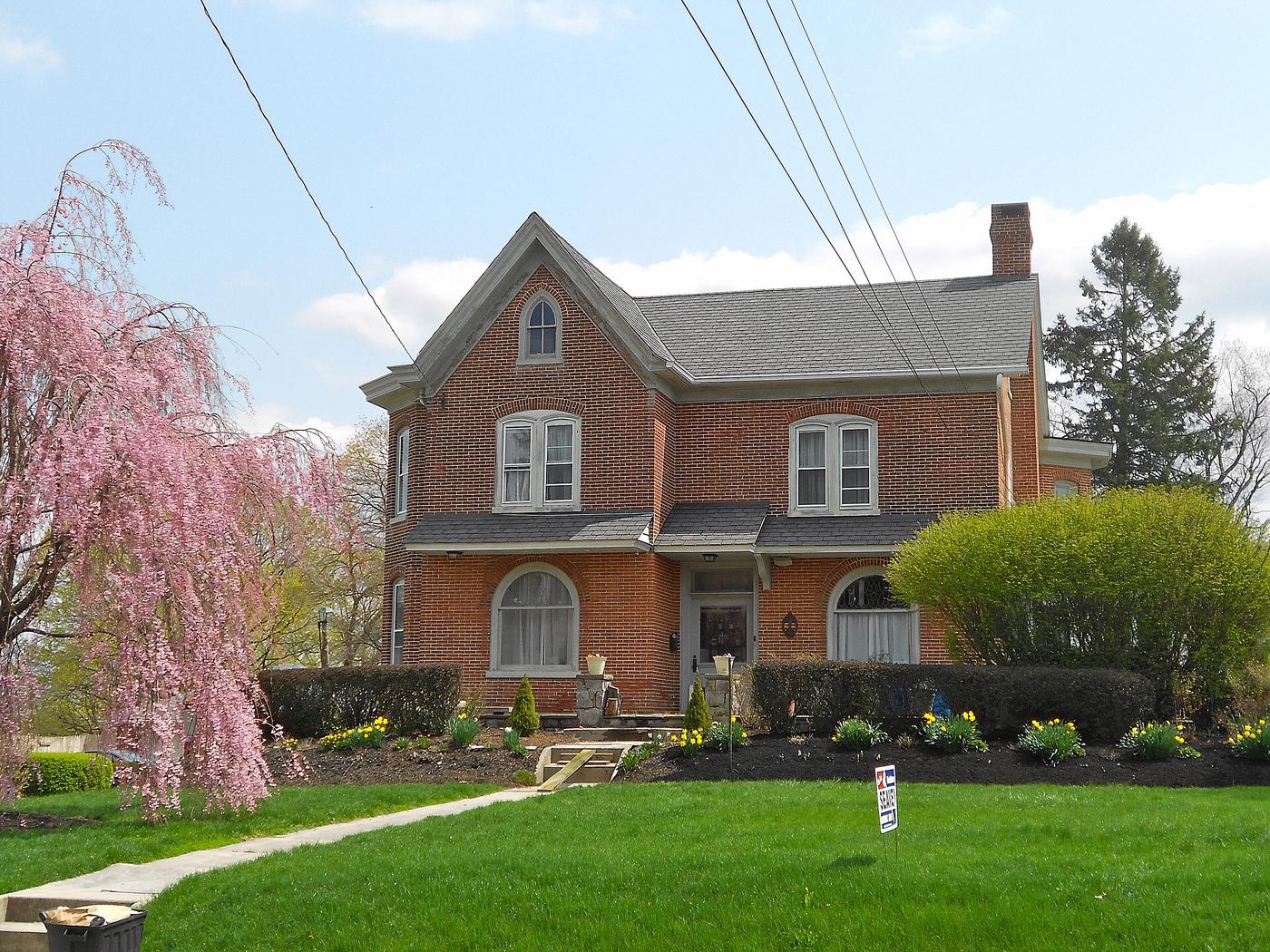 A brick house in West Grove under a weeping cherry. Mansard roof, arched windows, and the south-county price that keeps a file inside the USDA rules.