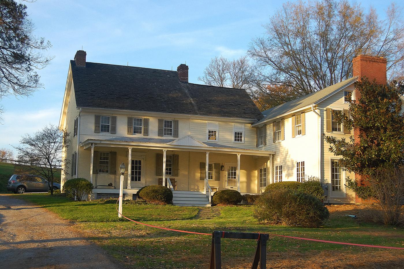 A house in Exton, cream stucco with a stone chimney and a porch along the front, on the kind of lot that used to be a farm.
